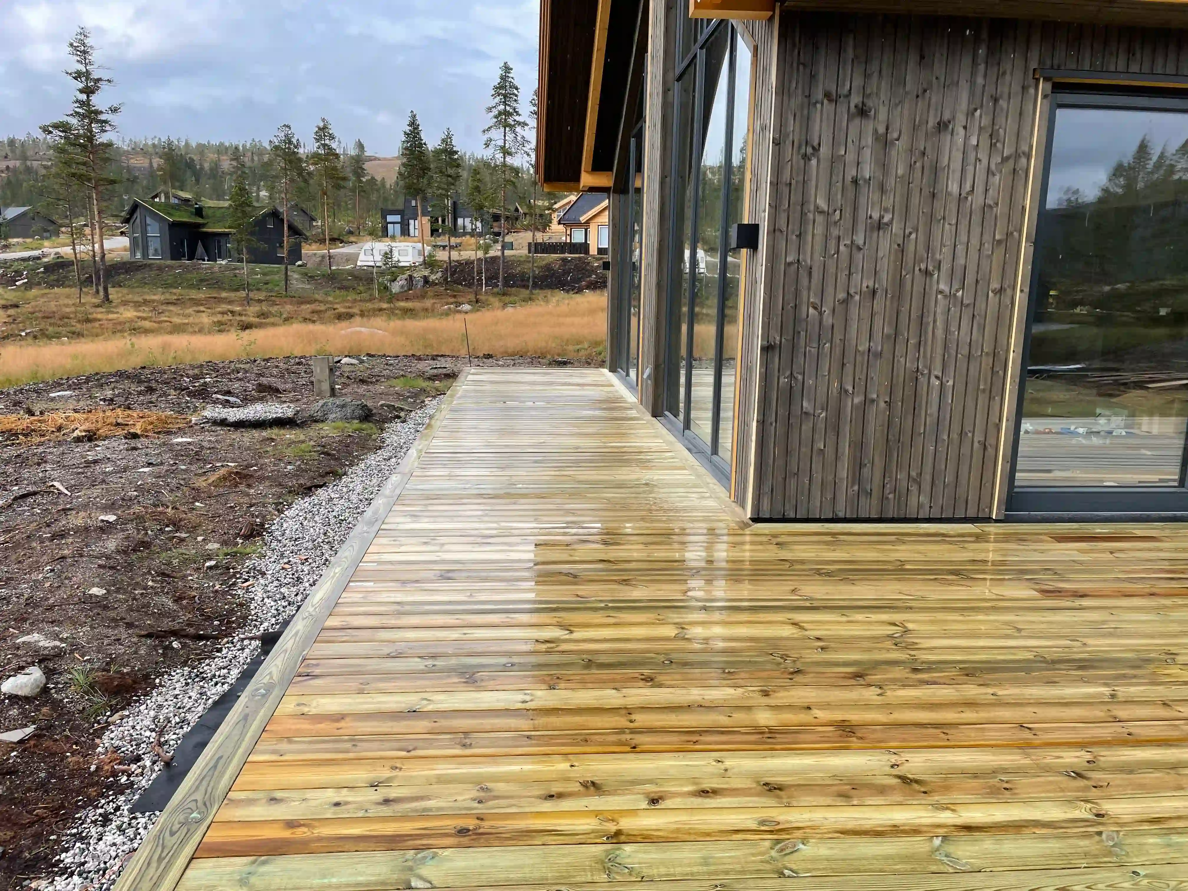 Våt treterrasse ved mørk fjellhytte.