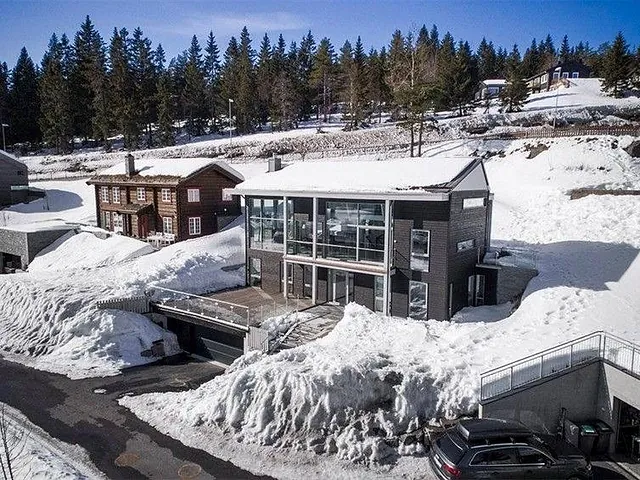 Moderne hus i snødekt landskap med glassfasade.